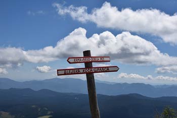 Planinski smerokaz na Mrežcah kaže dve smeri krožne planinske poti, ki vodi preko gore.