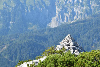 Stegovnik in kamniti možic na njegovem vrhu. V ozadju se vidijo strma pobočja najdaljšega karavanškega grebena, ki se imenuje Košuta.